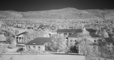Modern university dormitory building with students walking across campus grounds