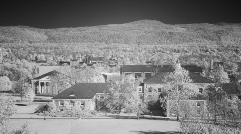 Modern university dormitory building with students walking across campus grounds